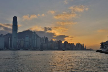 Hong Kong - 08 Aralık 2023: Günbatımında bulutlu gökyüzü altında modern şehir manzarasının manzarası 