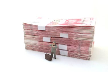 Bir işadamı Çin Yuan banknotları yığınının üzerinde duruyor.,
