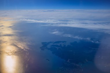 Uçak penceresinden bak. Su yüzeyindeki bulutlar.