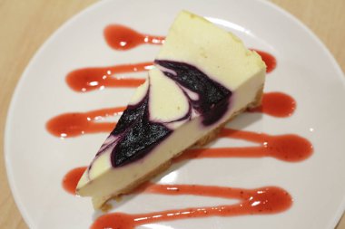 Beyaz tabakta bir dilim yaban mersinli kek.