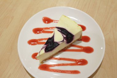 Beyaz tabakta bir dilim yaban mersinli kek.