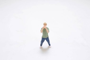 Sıradan giyinmiş bir adamın küçük oyuncak figürü tek başına karşısında duruyor.