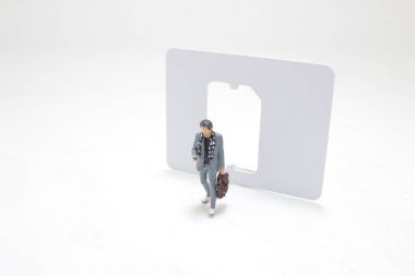 small model figure in a business suit walks through a large cut-out of a SIM card, clipart