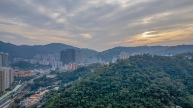 22 Aralık 2024 Yeşillik tepelerin yanındaki yüksek binaların bulunduğu şehir manzarası