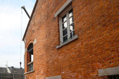 24 Aralık 2024. Tarihi kırmızı tuğla bina modern kentsel çevrenin ortasında duruyor.