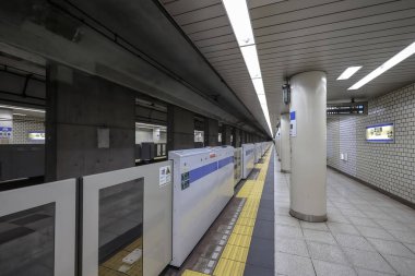 5 Aralık 2024 'te mavi bir tren, güvenlik bariyerleri ve yön işaretlerinin yanında durdu.,