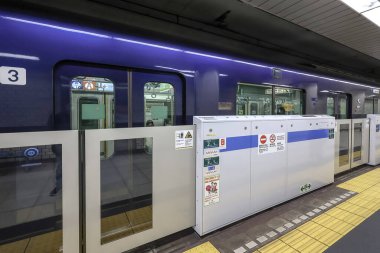 5 Aralık 2024 'te mavi bir tren, güvenlik bariyerleri ve yön işaretlerinin yanında durdu.,