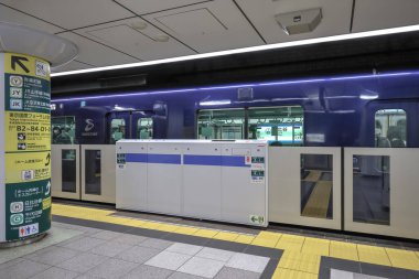 5 Aralık 2024 'te mavi bir tren, güvenlik bariyerleri ve yön işaretlerinin yanında durdu.,