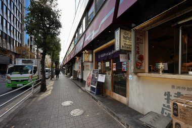 5 Aralık 2024 Yükseltilmiş demiryolu boyunca canlı mağaza tabelaları ve dekorasyonları olan bir Japon caddesi.,