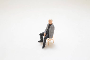 Sandalyede tek başına oturan bir adamı gösteren küçük ölçekli bir heykel.