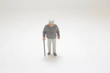 Bastonla yürüyen yaşlı bir adamın küçük plastik biblosu.,