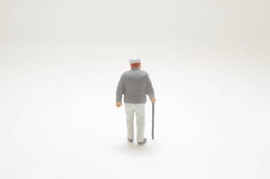 Bastonla yürüyen yaşlı bir adamın küçük plastik biblosu.,