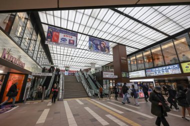 4 Aralık 2024 Yürüyen merdivenler, reklamlar ve müşterilerin yer aldığı hareketli bir alışveriş merkezi.