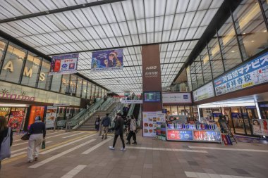 4 Aralık 2024 Yürüyen merdivenler, reklamlar ve müşterilerin yer aldığı hareketli bir alışveriş merkezi.