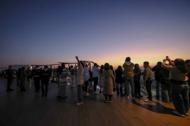 4 Aralık 2024 'te renkli gökyüzüne karşı siluet oluşturan insanlar,