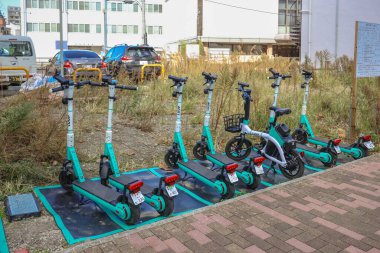 8 Aralık 2024 Bir sıra kenetlenmiş elektrikli scooter ve stratejik olarak bir bisiklet