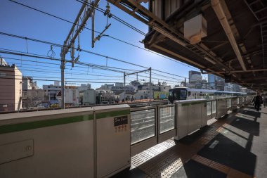 10 Aralık 2024 Parlak sarı bir tren hareketli bir şehir ortamından geçiyor