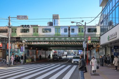 10 Aralık 2024 Dinamik şehir manzarasında yoğun bir yaya geçidinin üzerinde bir tren üstgeçidi var.