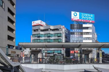 9 Aralık 2024 Tabelalı binaların bulunduğu hareketli bir şehir manzarası.