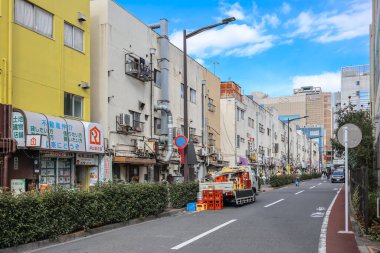 8 Aralık 2024 Çok katlı binalar, dükkanlar ve parlak gökyüzü olan canlı bir şehir caddesi.