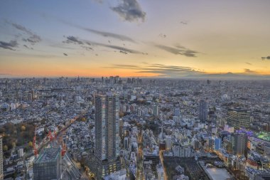 6 Aralık 2024 Günbatımı Aydınlatılmış gökdelenlerle süslenmiş modern bir şehir manzarası