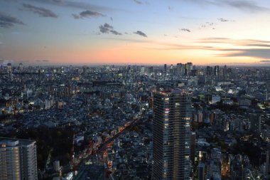 6 Aralık 2024 Günbatımı Aydınlatılmış gökdelenlerle süslenmiş modern bir şehir manzarası