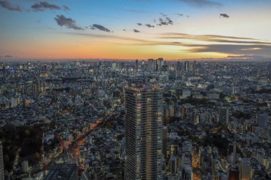 6 Aralık 2024 günbatımında bir metropolün hava görüntüsü, canlı ışıkları gösteriyor.