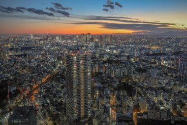 6 Aralık 2024 günbatımında bir metropolün hava görüntüsü, canlı ışıkları gösteriyor.