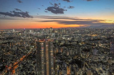 6 Aralık 2024 günbatımında bir metropolün hava görüntüsü, canlı ışıkları gösteriyor.