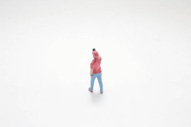 Sıradan giyinmiş, elinde akıllı telefon tutan minyatür bir figür.