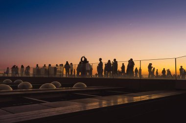 4 Aralık 2024 'te renkli gökyüzüne karşı siluet oluşturan insanlar,