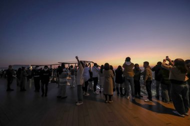 4 Aralık 2024 'te renkli gökyüzüne karşı siluet oluşturan insanlar,