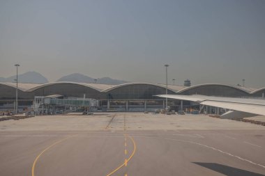 22 Mart 2025 uçak penceresi bir kanat, pist ve modern havaalanı terminalini gösteriyor.