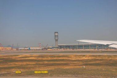 22 Mart 2025 uçak penceresi bir kanat, pist ve modern havaalanı terminalini gösteriyor.