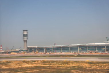 22 Mart 2025 uçak penceresi bir kanat, pist ve modern havaalanı terminalini gösteriyor.