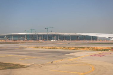 22 Mart 2025 uçak penceresi bir kanat, pist ve modern havaalanı terminalini gösteriyor.