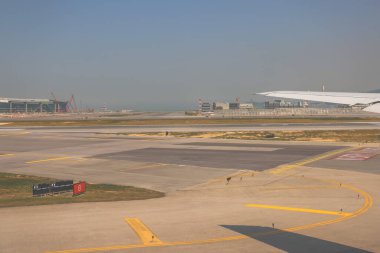 22 Mart 2025 uçak penceresi bir kanat, pist ve modern havaalanı terminalini gösteriyor.