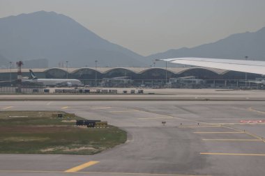 22 Mart 2025 uçak penceresi bir kanat, pist ve modern havaalanı terminalini gösteriyor.