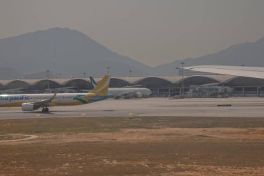 22 Mart 2025 uçak penceresi bir kanat, pist ve modern havaalanı terminalini gösteriyor.