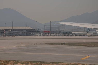 22 Mart 2025 uçak penceresi bir kanat, pist ve modern havaalanı terminalini gösteriyor.