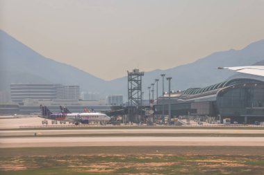 22 Mart 2025 uçak penceresi bir kanat, pist ve modern havaalanı terminalini gösteriyor.