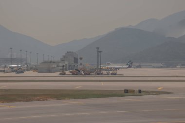 22 Mart 2025 uçak penceresi bir kanat, pist ve modern havaalanı terminalini gösteriyor.