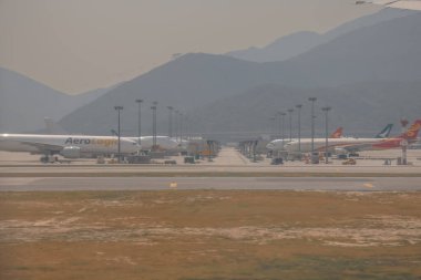 22 Mart 2025 uçak penceresi bir kanat, pist ve modern havaalanı terminalini gösteriyor.