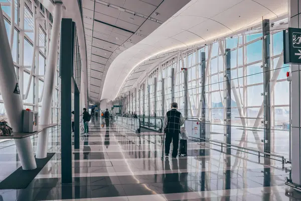 22 Mart 2025 Yolcular parlak ışıklandırmalı lüks ve modern bir havaalanı terminalinden geçecekler.