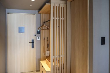 24 Mart 2025 Ahşap dekor unsurları içeren temiz otel odası girişi,