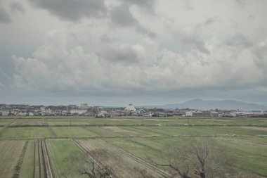 24 Mart 2025 Tarım alanları ve bulutlu bir gökyüzü altında dağınık binalar