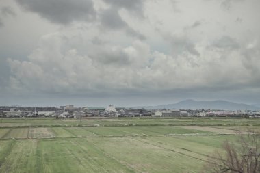 24 Mart 2025 Tarım alanları ve bulutlu bir gökyüzü altında dağınık binalar