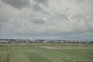 24 Mart 2025 Tarım alanları ve bulutlu bir gökyüzü altında dağınık binalar