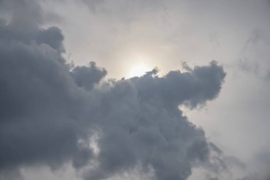 Güneş ışınları yoğun, karanlık bulutların arasından süzülüyor.