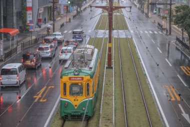 Çağdaş bir tramvay yağmurlu şehirlerde yeşil yollar boyunca seyahat ediyor.,